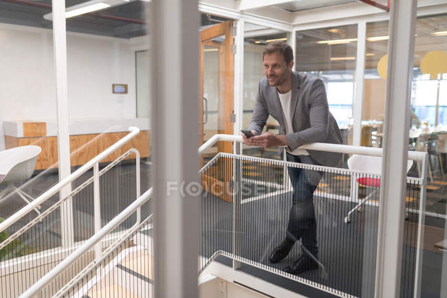 Empresário feliz usando telefone celular no escritório — Fotografia de Stock