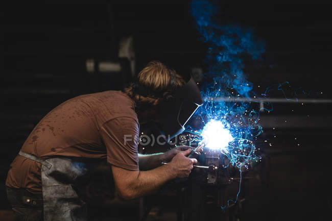 Blacksmith using a welding torch in workshop — Stock Photo