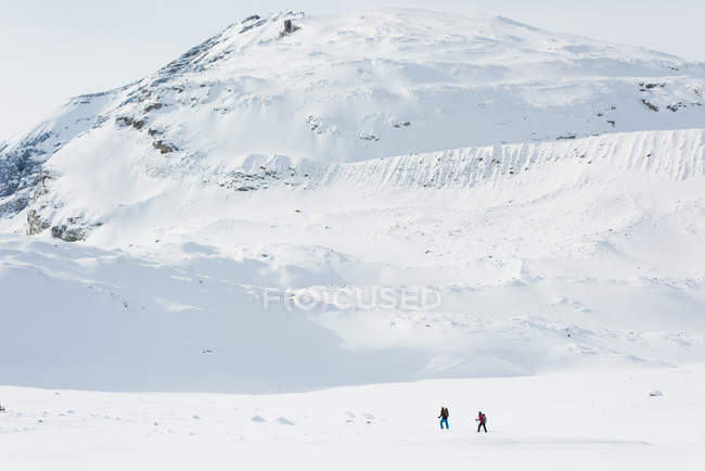 Couple walking on a snow capped mountain during winter — Stock Photo