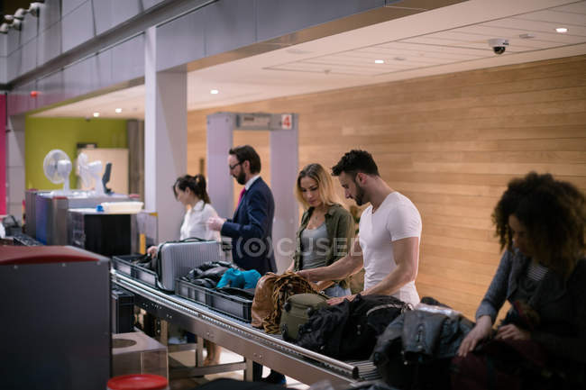 Comutadores levando sua bagagem do carrossel de bagagem no aeroporto — Fotografia de Stock