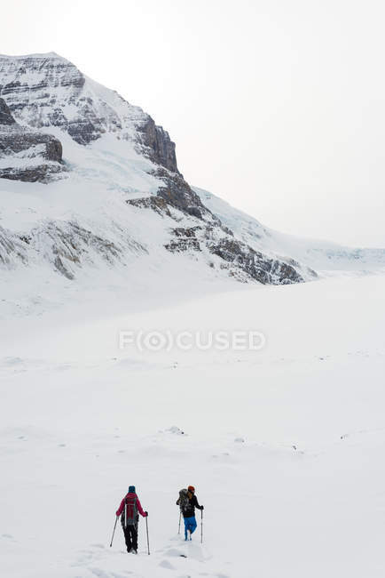Couple marchant sur une montagne enneigée pendant l'hiver — Photo de stock