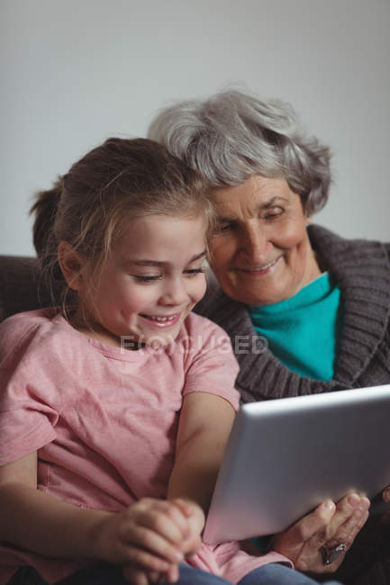 Großmutter und Enkelin mit digitalem Tablet im heimischen Wohnzimmer — Stockfoto