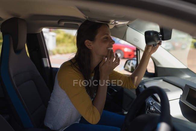 Mulher olhando para o espelho retrovisor em um carro — Fotografia de Stock
