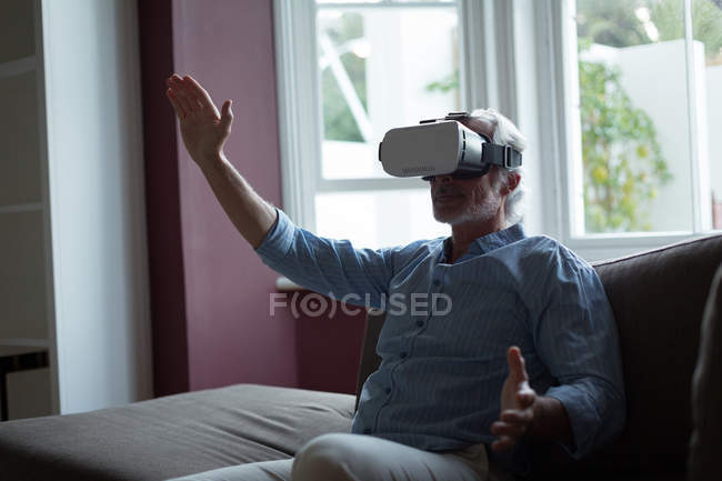 Hombre mayor usando auriculares de realidad virtual - foto de stock