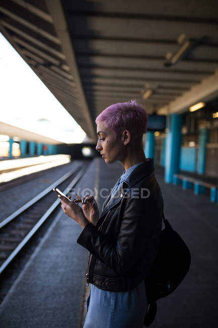 Stilvolle Frau nutzt Handy am Bahnhof — Stockfoto