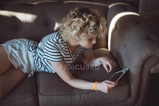 Femme utilisant une tablette numérique dans le salon à la maison — Photo de stock