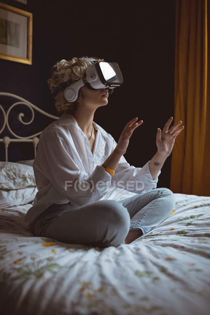 Mujer usando auriculares de realidad virtual en el dormitorio en casa - foto de stock