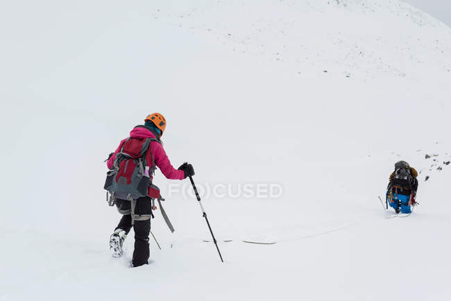 Casal andando em uma montanha coberta de neve durante o inverno — Fotografia de Stock