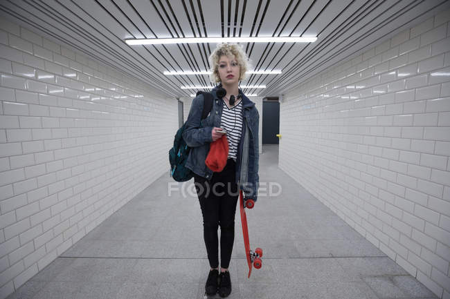 Mujer joven de pie con monopatín en el metro - foto de stock