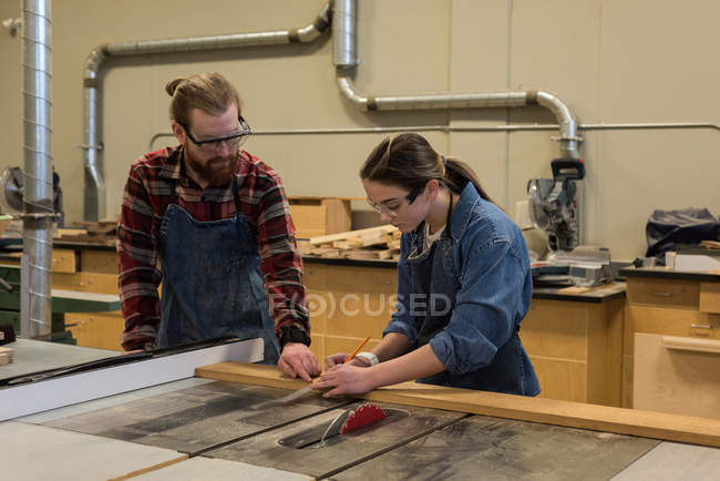 Carpinteros masculinos y femeninos trabajando juntos en el taller - foto de stock
