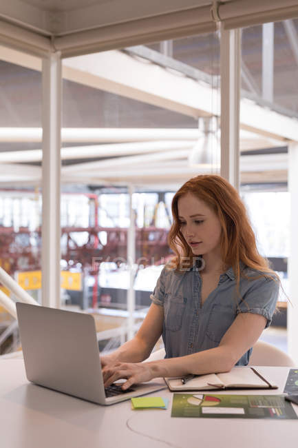 Executivo feminino usando laptop na mesa no escritório — Fotografia de Stock
