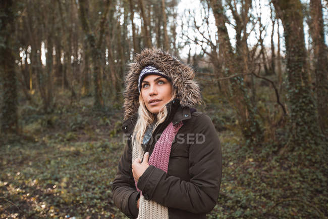 Jovem mulher de capuz em pé na floresta — Fotografia de Stock