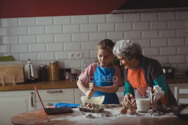 Grand-mère et petite-fille préparant des biscuits dans la cuisine à la maison — Photo de stock