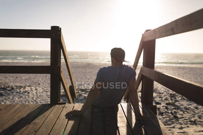 Surfista masculino relaxando na torre de vigia na praia ao entardecer — Fotografia de Stock
