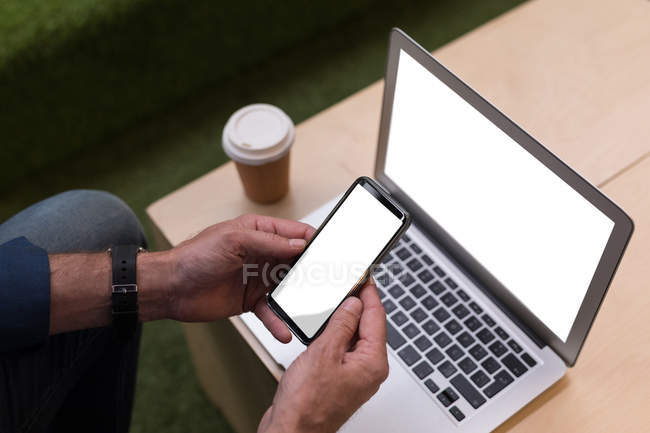 Cropped image of businessman using mobile phone in office, blank screens — Stock Photo