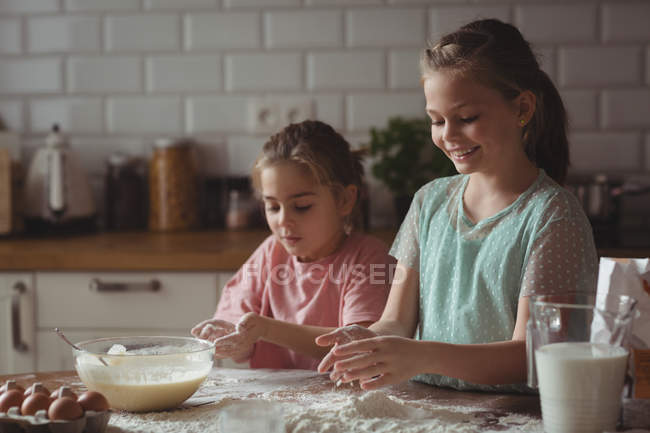 Hermanos preparando magdalena en la cocina en casa - foto de stock
