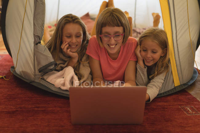 Irmãos felizes usando laptop em uma tenda em casa — Fotografia de Stock