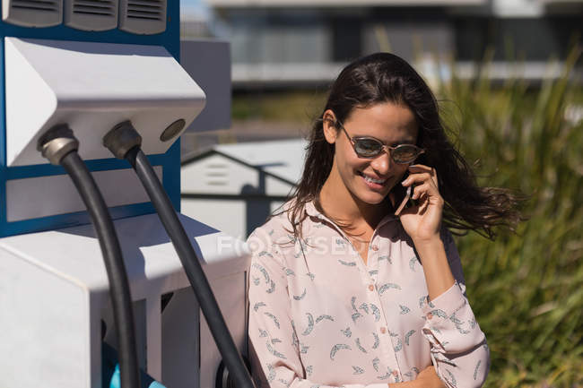 Mulher bonita falando no telefone celular na estação de carregamento — Fotografia de Stock
