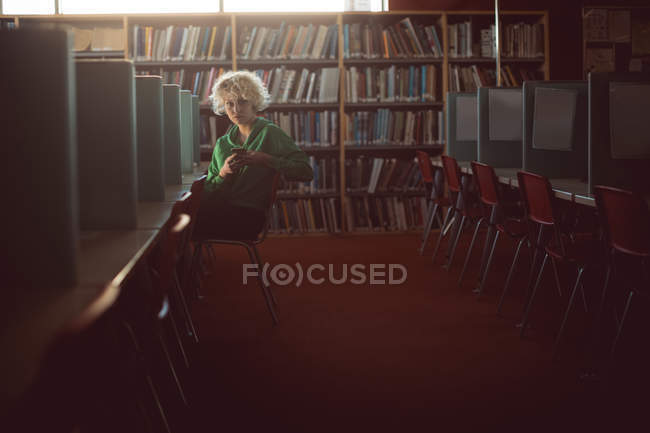 Junge Frau benutzt Handy in Bibliothek — Stockfoto