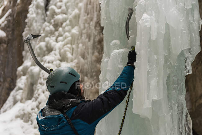 Male rock climber climbing ice mountain during winter — Stock Photo