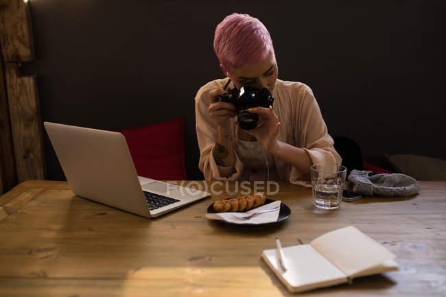 Elegante mujer haciendo clic en la foto del desayuno con cámara en el restaurante - foto de stock