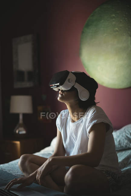 Mulher usando laptop com fone de ouvido realidade virtual no quarto em casa — Fotografia de Stock