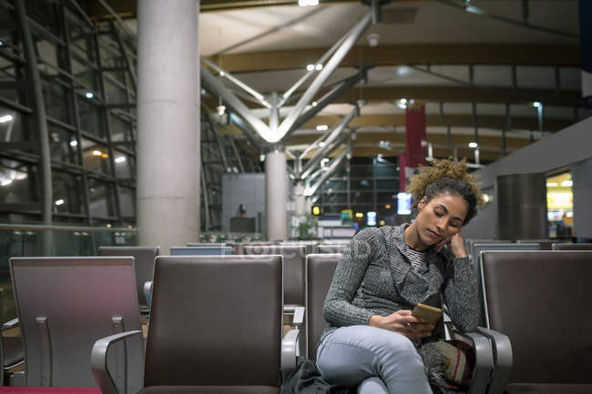 Frau benutzte Handy im Wartebereich am Flughafen — Stockfoto