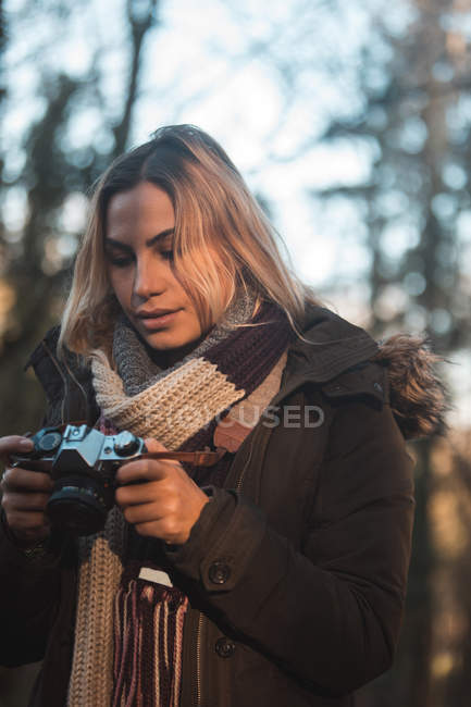 Jeune femme examinant des photos sur appareil photo numérique — Photo de stock