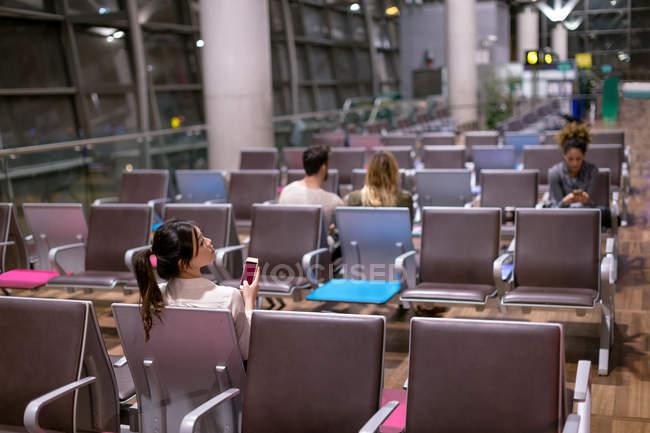 Woman using mobile phone in waiting area at airport — Stock Photo