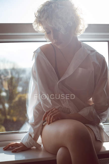 Продумана жінка сидить біля вікна вдома — стокове фото