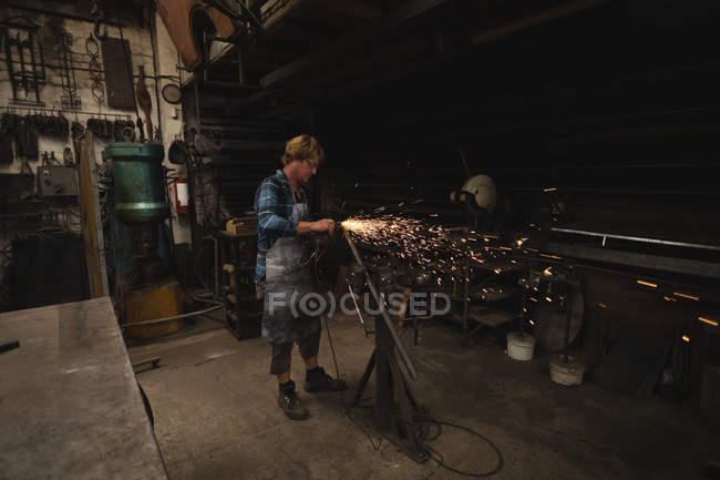 Schmied schleift Metallstange mit Schleifmaschine n Werkstatt — Stockfoto