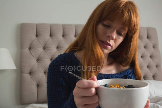 Femme prenant le petit déjeuner dans la chambre à coucher à la maison — Photo de stock