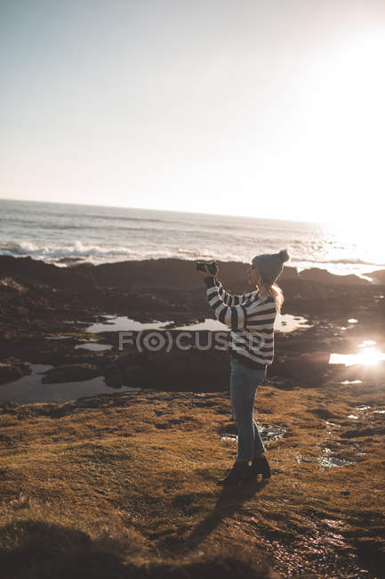 Donna cliccando foto con macchina fotografica in spiaggia — Foto stock