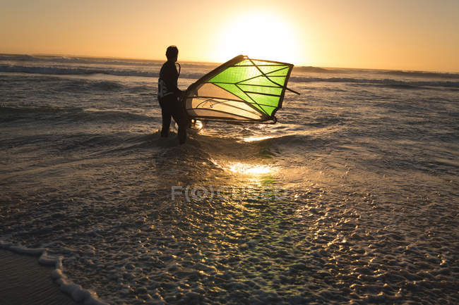 Surfeur masculin surfant avec planche de surf et cerf-volant à la plage — Photo de stock