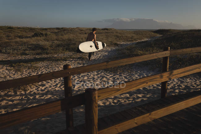 Чоловічий серфер, що йде з дошкою для серфінгу на пляжі — стокове фото