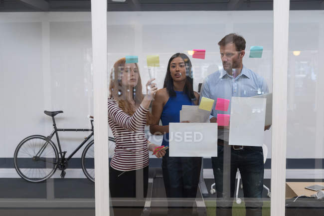 Business colleagues discussing over sticky notes in office — Stock Photo