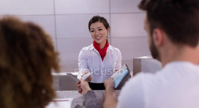 Asistente de Arline interactuando con los viajeros en el mostrador en el aeropuerto - foto de stock