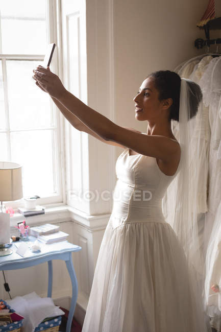 Mariée mixte prenant selfie avec téléphone portable en boutique — Photo de stock