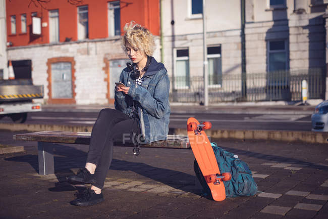 Женщина, использующая мобильный телефон на городской улице в солнечный день — стоковое фото