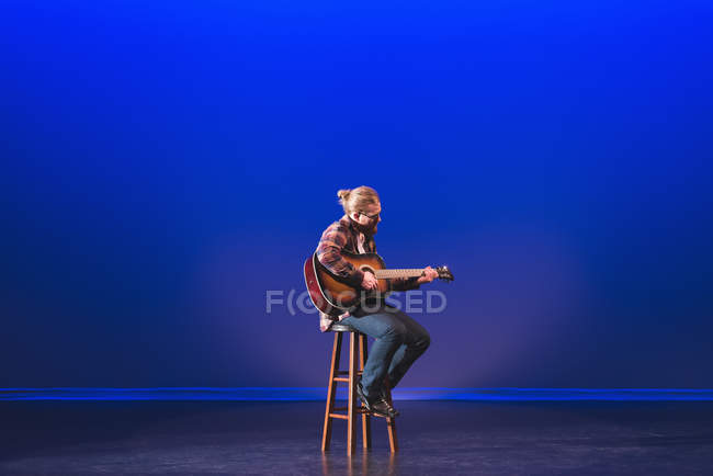 Man playing guitar on stage at theatre — Stock Photo