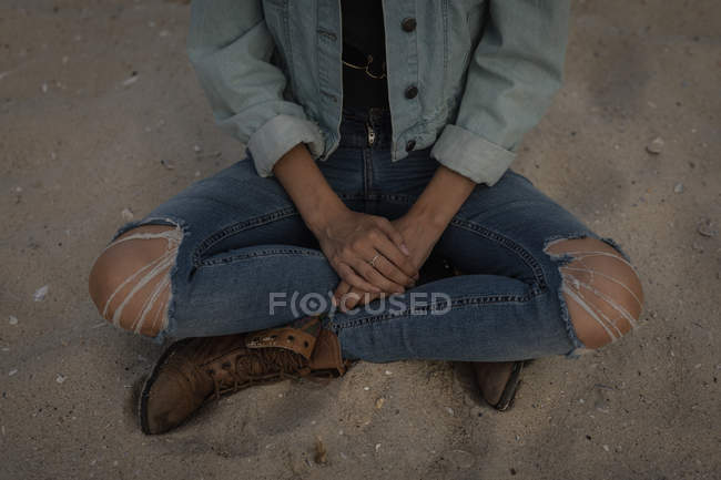 Gros plan d'une femme assise sur une plage au crépuscule — Photo de stock