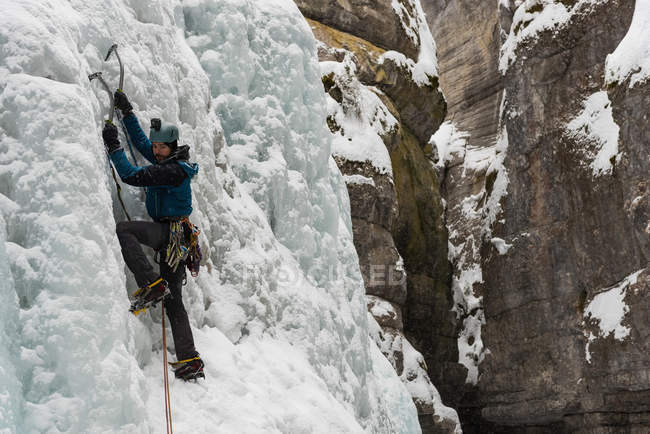 Männlicher Bergsteiger besteigt Eisberg im Winter — Stockfoto