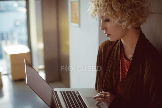 Jovem mulher usando laptop na biblioteca — Fotografia de Stock