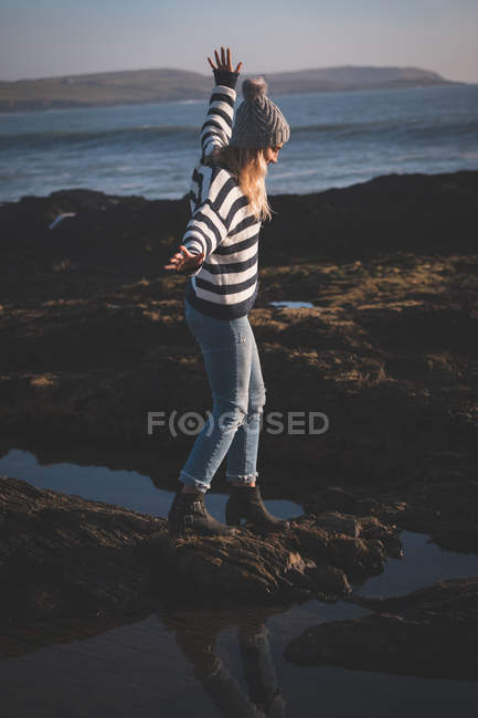 Frau läuft an einem sonnigen Tag mit ausgestreckten Armen am Strand — Stockfoto