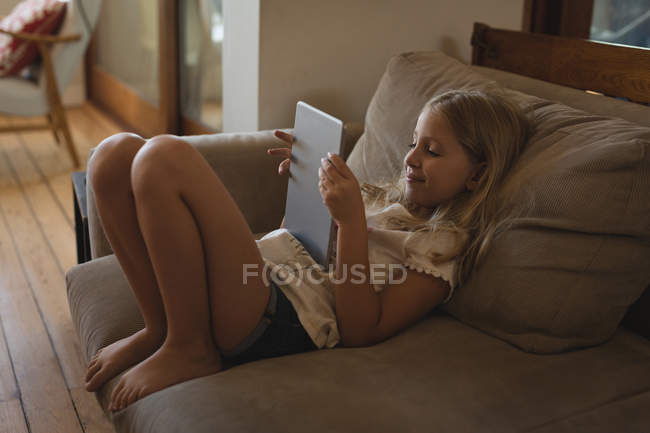 Расслабленная девушка с помощью цифрового планшета в гостиной дома — стоковое фото