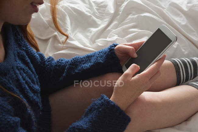 Woman using mobile phone in bedroom — Stock Photo