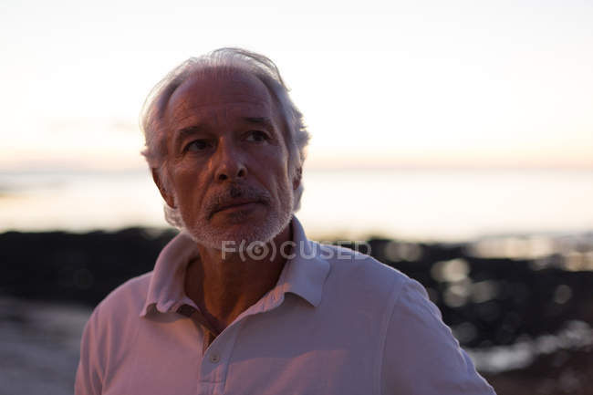 Nachdenklicher Senior steht in der Abenddämmerung in Strandnähe — Stockfoto