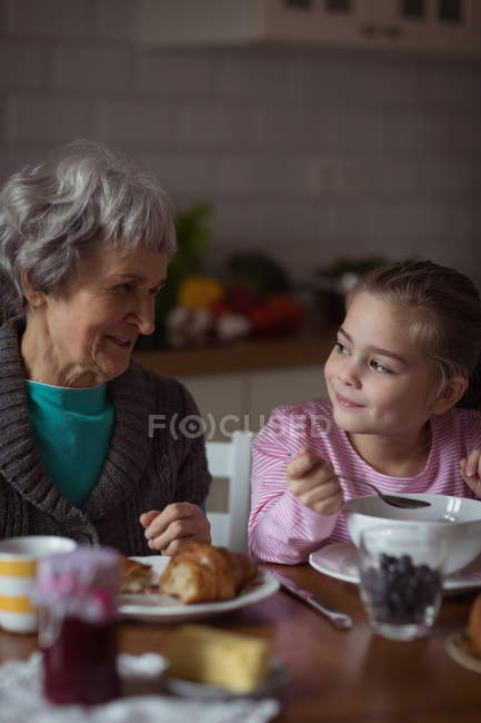 Avó e neta tomando café da manhã na cozinha em casa — Fotografia de Stock