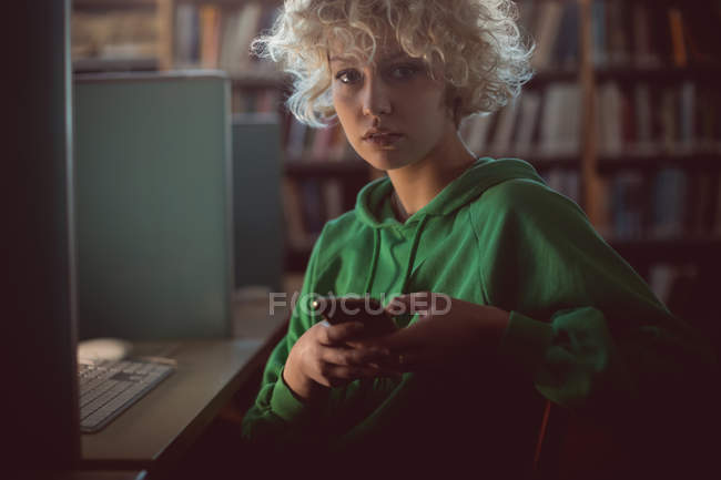 Портрет молодої жінки з використанням мобільного телефону в бібліотеці — стокове фото
