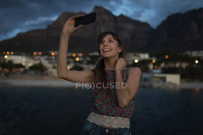 Giovane donna scattare selfie con il telefono cellulare in spiaggia — Foto stock